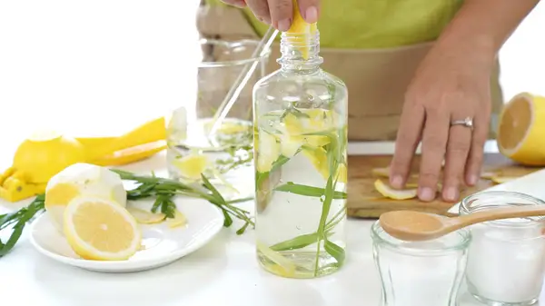 Woman creating oil product in kitchen that includes fruit
