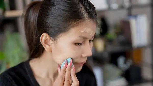A woman applying foundation with a sponge
