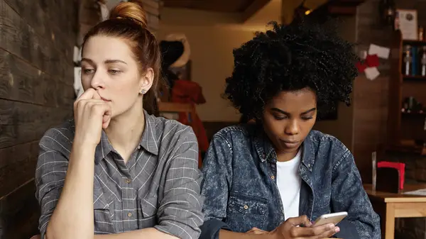 Queer couple, one looking at phone