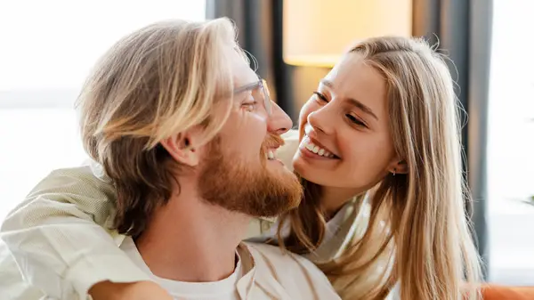 A blonde couple smiling at each other with the woman