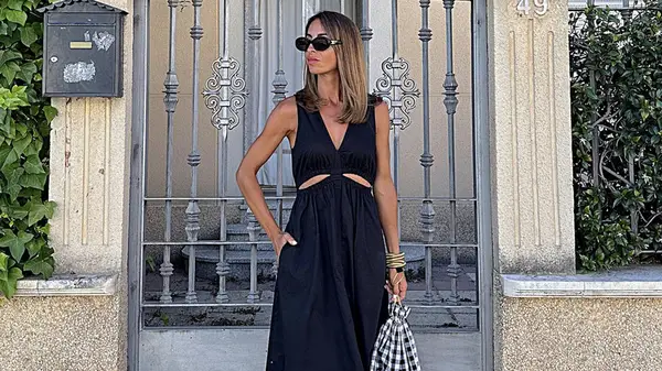 Woman in black dress poses in front of gate