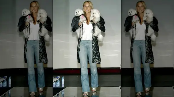 Vanessa Trump walking the runway wearing blue jeans and holding two small white dogs