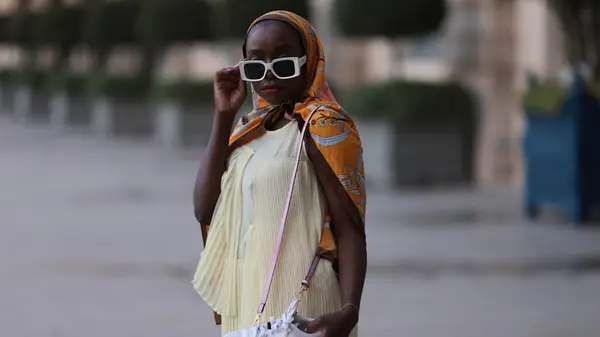 Suzan Mutesi rocking a butter yellow dress with a bright scarf during Paris Fashion Week