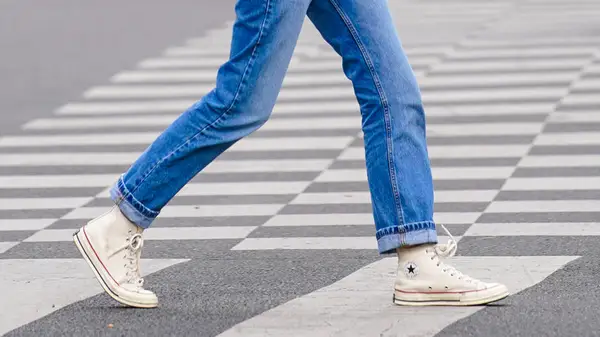 Snapshot of legs wearing cuffed denim and sneakers walking in the street
