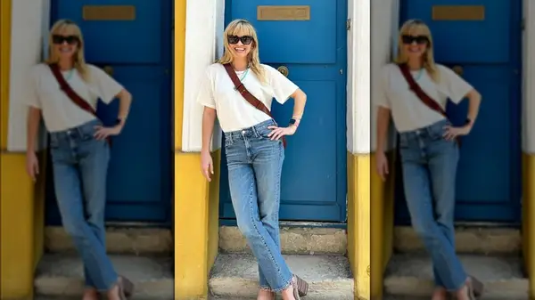 Reese Witherspoon in jeans and a white t-shirt in front of a blue door