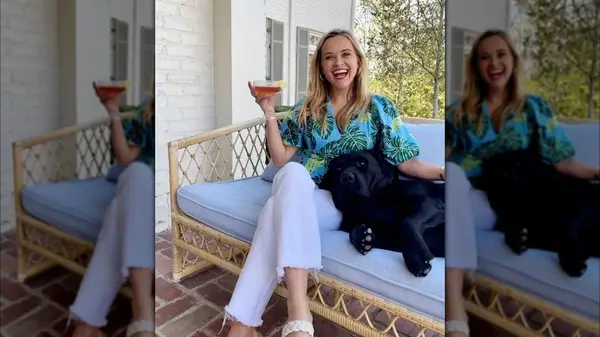 Reese Witherspoon on Instagram in white denim holding a martini next to her dog