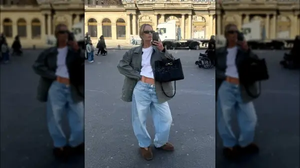 A woman photographing herself in a mirror while wearing baggy jeans