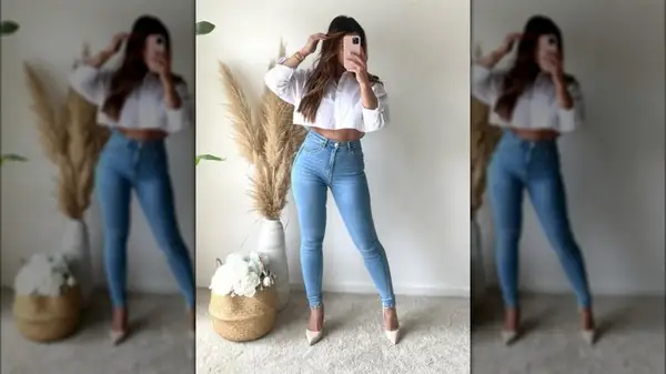 A woman taking a photo of herself in the mirror and wearing skinny jeans