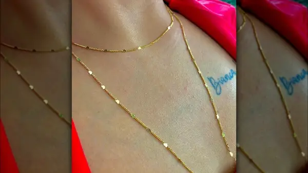 Person wearing two gold necklaces