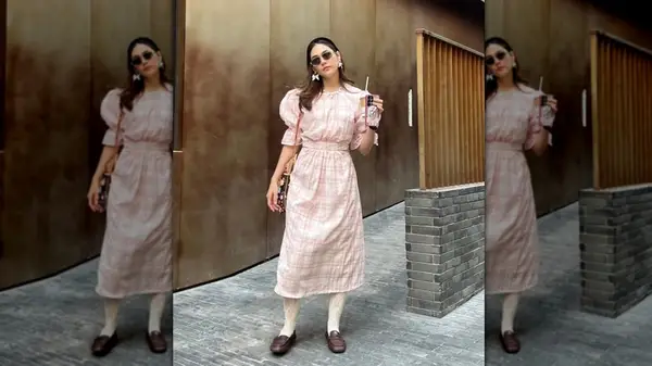 A woman standing on the sidewalk in a pink gingham dress