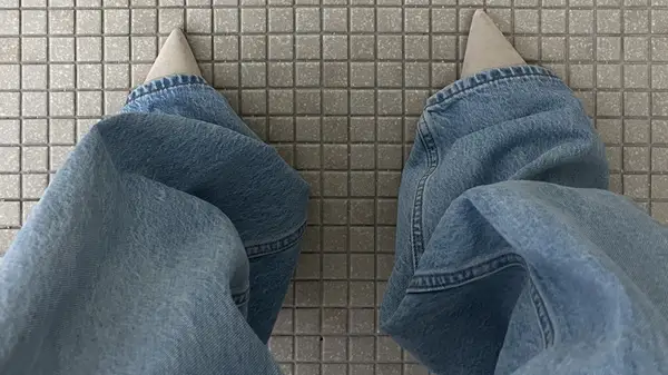 Someone standing in baggy jeans and pointed-toe heels