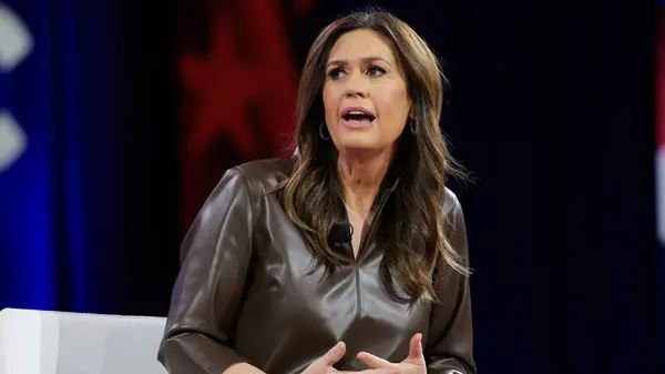 Sarah Huckabee Sanders wearing a brown leather blouse while speaking