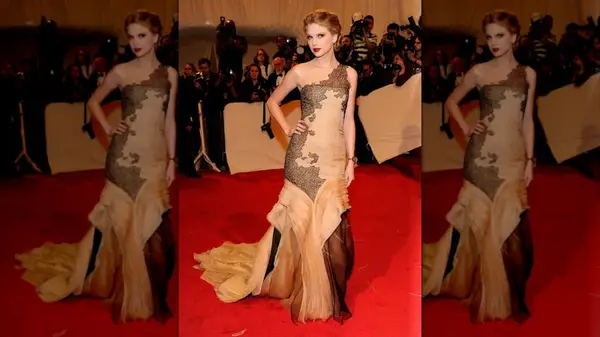 Taylro Swift wearing a pink gown with black lace accents on the red carpet