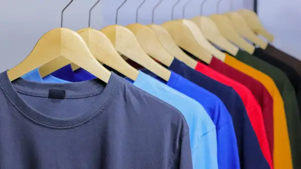 Rack of colorful t-shirts on wooden hangers