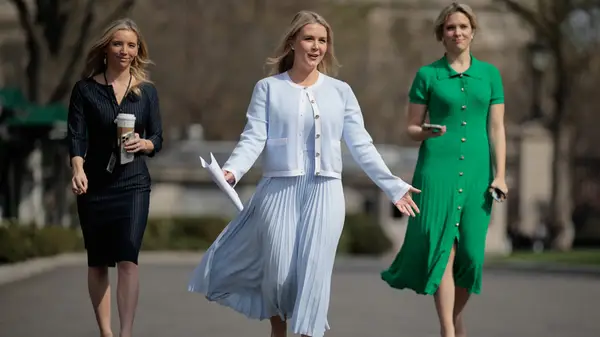 Karoline Leavitt walks up to a group of reporters outside of the West Wing in March 2025 wearing a blue skirt and sweater