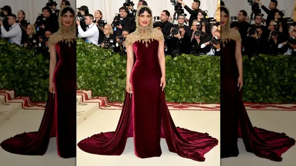 Priyanka Chopra posing in a red velvet dress and beaded hood at the 2018 Met Gala