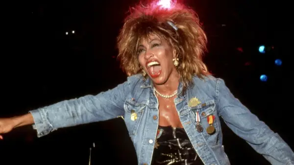 Tina Turner performing on stage in a denim jacket