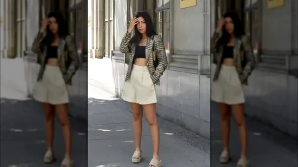 A woman on a sidewalk wearing white Bermuda shorts and a blazer