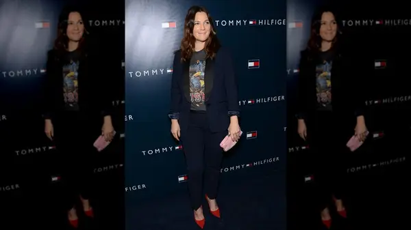 Drew Barrymore posing in a blue suit worn over a graphic tee at a Tommy Hilfiger event