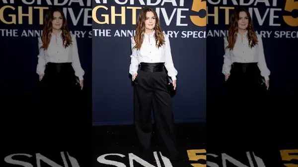 Drew Barrymore posing in black trousers with a silk cumberbund and a white button-up