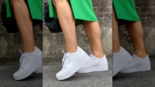 Woman wearing white platform sneakers with green skirt