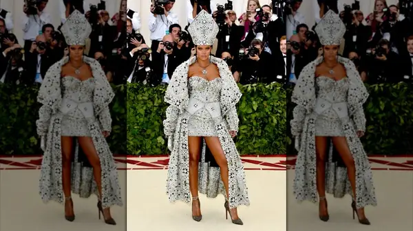 Rihanna at the 2018 Met Gala in a rhinestone and pearl encrusted mini dress with cape and head piece