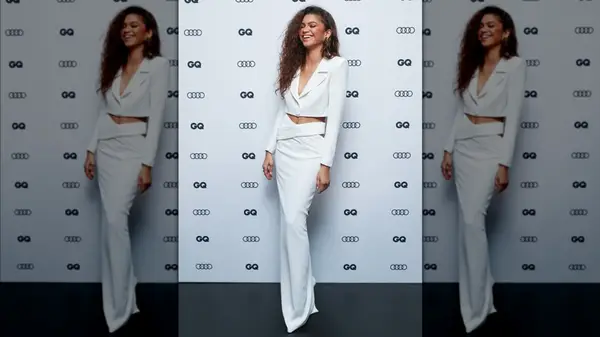 Zendaya laughing while wearing a monochrome blazer and skirt set