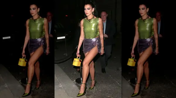 Dua Lipa walking in a green and purple outfit
