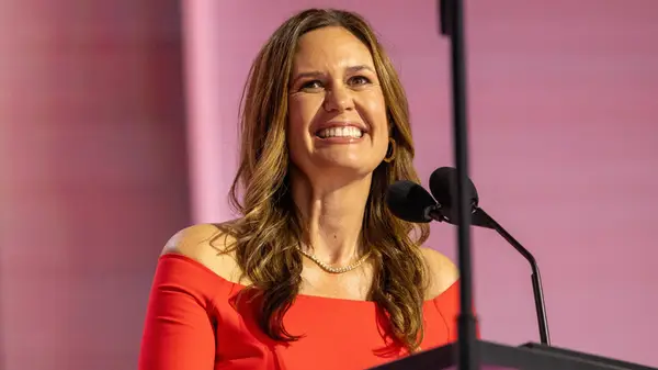 Sarah Huckabee Sanders at an event in a red off-the-shoulder dress