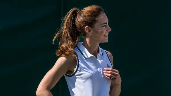 Kate Middleton smiles while wearing a sleeveless polo shirt