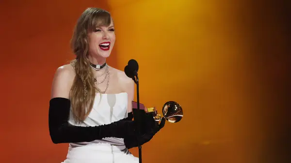 Taylor Swift on stage holding a Grammy statue
