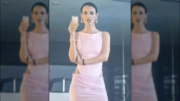 Woman wearing a pink bathing suit and pink skirt holding a glass of champagne