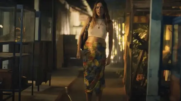 A woman in a white crop top and floral skirt