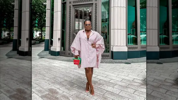 Woman posing in a red and white striped shirtdress on a city sidewalk