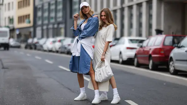 Two women wearing dresses while posing in the street