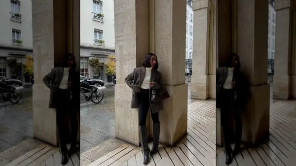 Instagram influencer posing against a column wearing dark skinny pants and tall boots