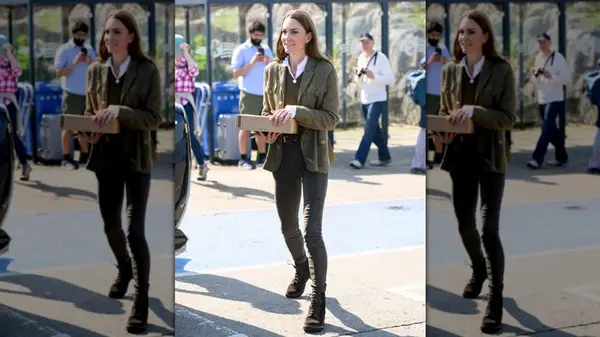 Kate Middleton holding a box wearing an olive-colored blazer, skinny jeans, and lace-up boots