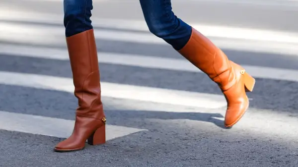 Close-up of woman crossing the street while wearing brown boots and skinny jeans