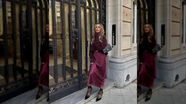 A woman standing outside in a cherry red skirt and sweater