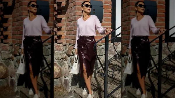 A woman standing outside in a cherry skirt, a pink sweater and white shoes