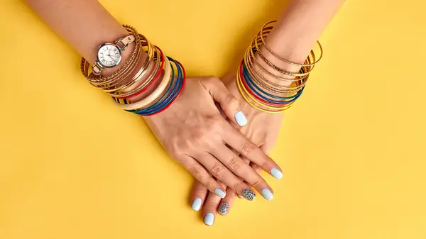 woman wearing watch and bracelets against yellow background
