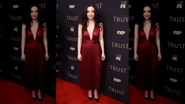 Mikey Madison smiling in a dark red dress at an FX event