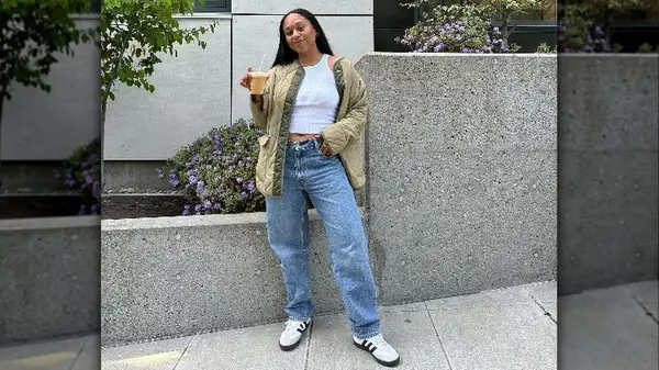 Person posing with iced coffee in jeans and a jacket