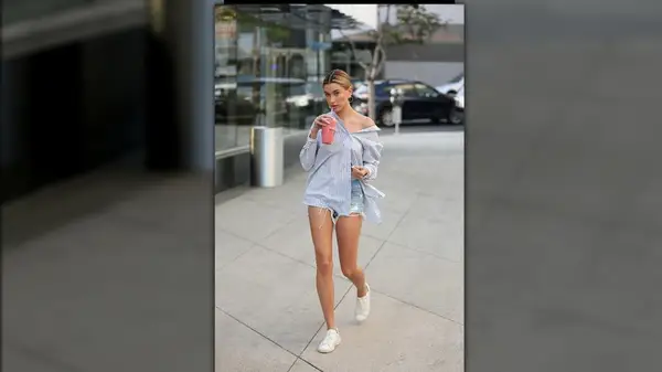 Hailey Bieber wearing oversized button-down and jean shorts