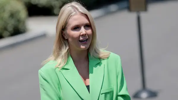Karoline Leavitt in a green blazer while speaking outside