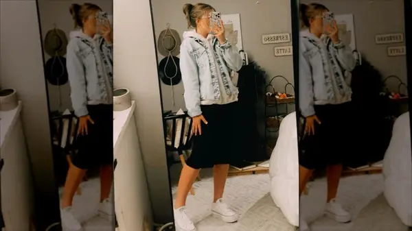 A woman in an oversized denim jacket with a hoodie