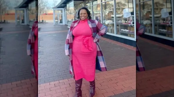 A woman in a pink knitted dress with a coat and boots