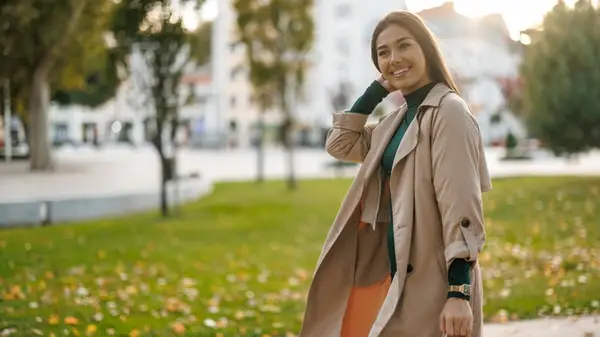 A woman walking wearing a trench coat in fall