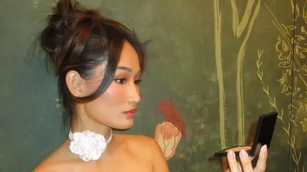 Isabel Tan looks into a compact mirror