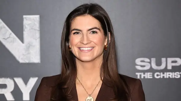 Kaitlan Collins smiling in a brown blazer